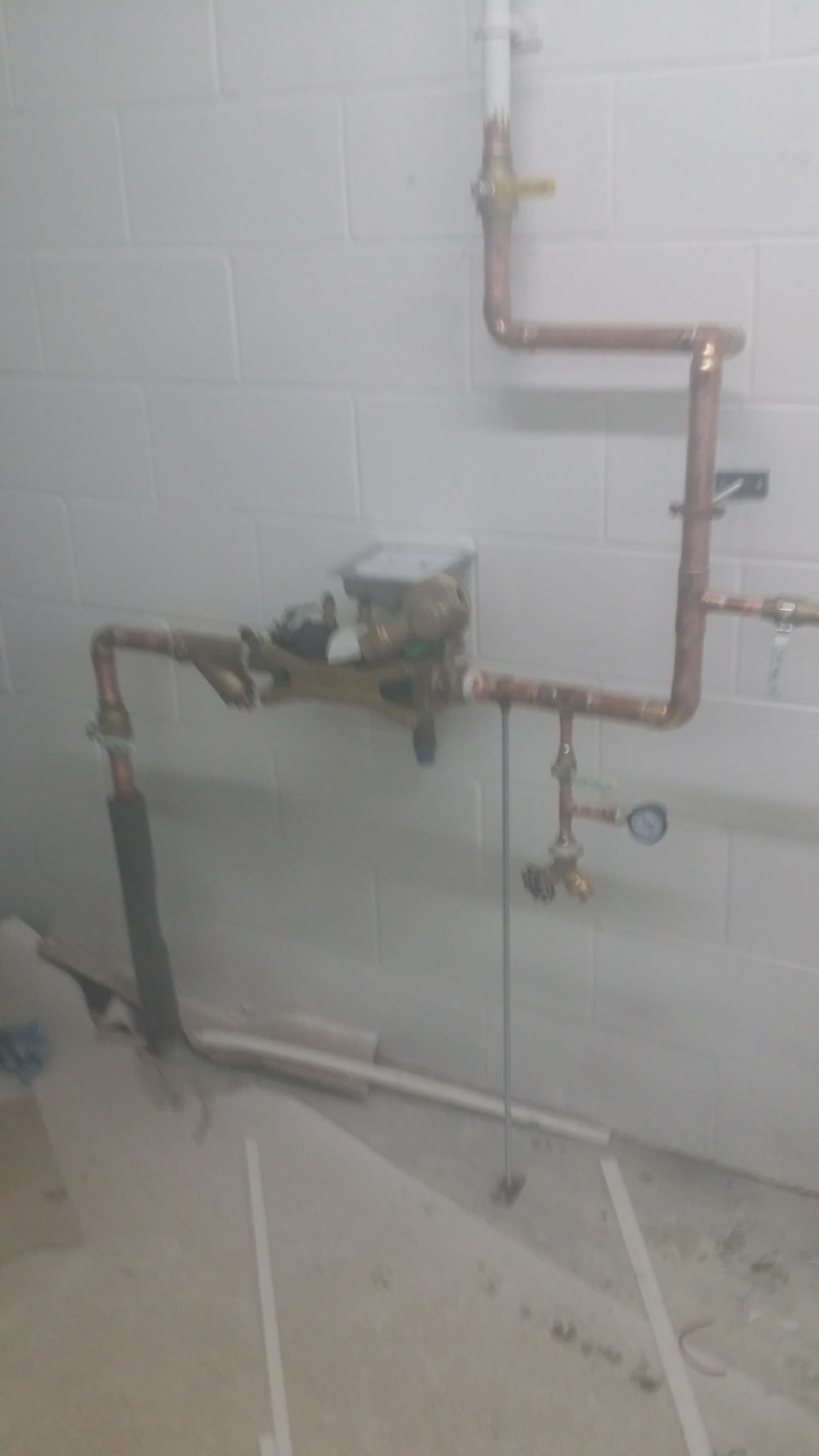 Copper supply piping with valves and pressure gauge on a commercial wall