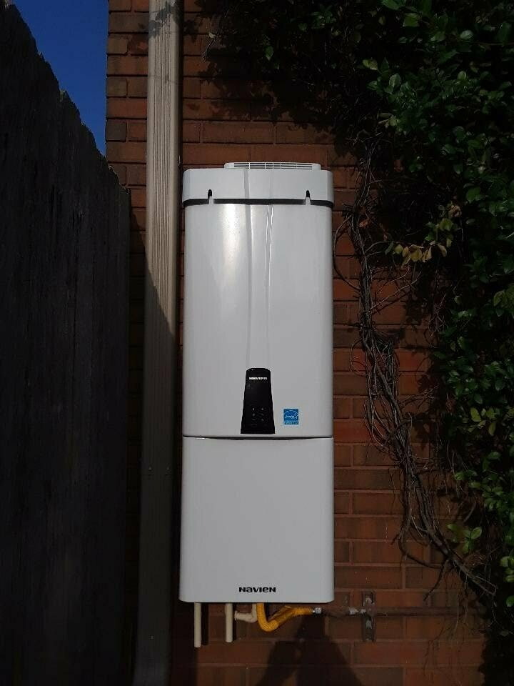 Navien tankless water heater mounted on an exterior brick wall