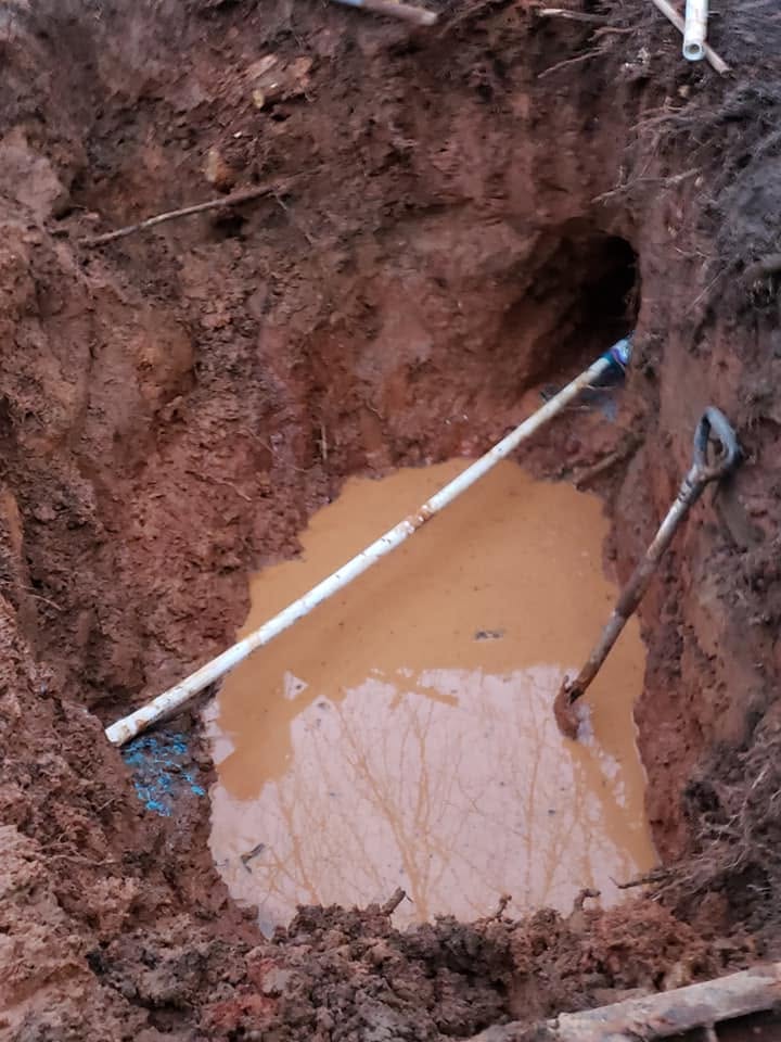 White PVC main line laid through an excavated repair pit